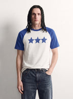 PVTLTD* Blue Raglan Tee, close-up of the speckled three-star chest print on the off-white body