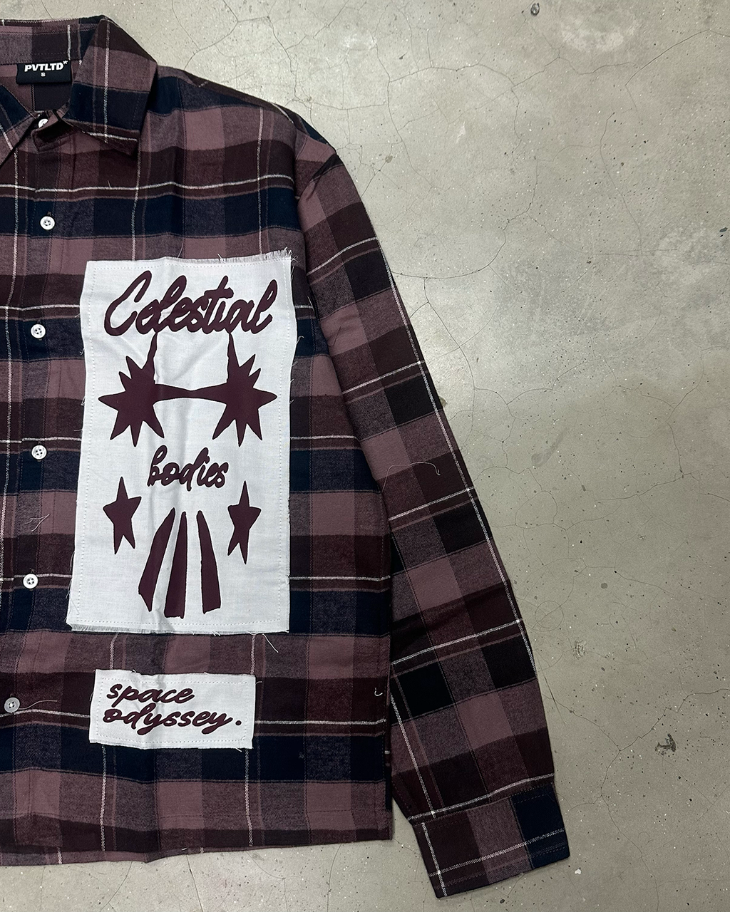 Celestial Bodies and space odyssey patches on the PVTLTD* Cosmic Flannel, laid on concrete