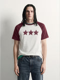 PVTLTD* Red Raglan Tee, close-up of the speckled three-star chest print on the off-white body